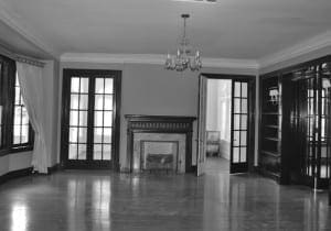 Dark wood paneling, fireplace, and double doors in a large room.