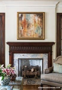 Gold-framed abstract painting above a dark wood mantel.