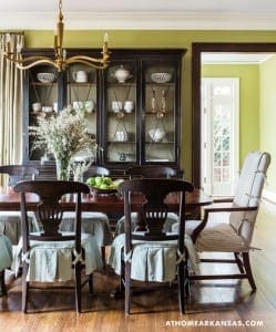 Dark wood dining room with gold chandelier and green walls.