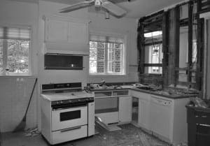 Black and white kitchen renovation with exposed framing and appliances.
