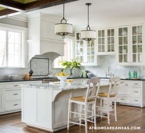 White kitchen with marble island and glass-front cabinets.
