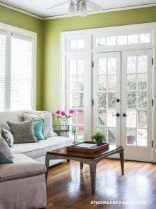 Green room with a light-colored sofa, coffee table, and large windows.