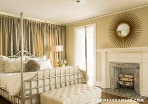 Four-poster bed with upholstered bench and ornate mirror.