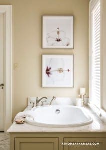Beige wall with two framed floral prints and a window.