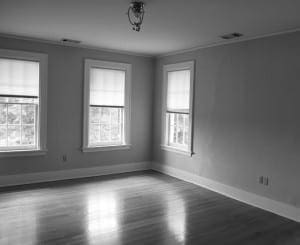 Gray room with hardwood floor, two windows, and a light fixture.