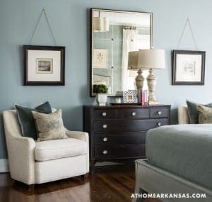 Blue wall with two framed artworks and a mirror.