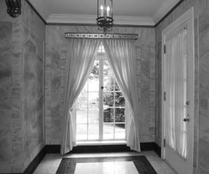 Marble hallway with chandelier, drapes, and window view.