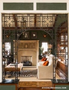 Ornate wrought-iron screen separates interior spaces with a fireplace.
