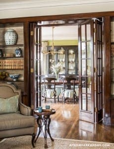 Dark wood panel doors lead to a dining room with a green table.