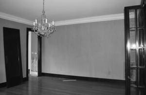 Gray wallpapered room with a chandelier and dark wood paneling.