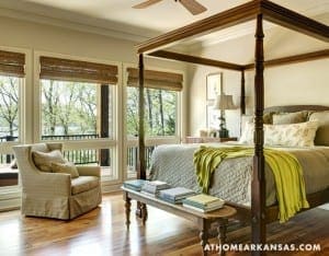 Four-poster bed in a bedroom with windows and greenery.