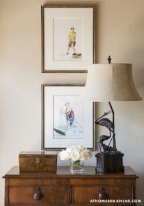 Two framed watercolor paintings and a lamp on a wooden dresser.