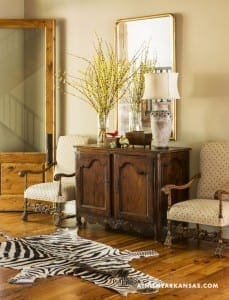 Wooden cabinet, zebra rug, and chairs in a room.