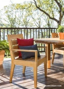 Wooden deck with teak chairs, red pillow, and potted plants.