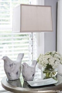 Gray ceramic bird sculptures on a glass table with a floral arrangement.