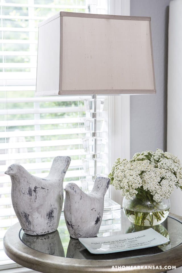Gray ceramic bird sculptures on a glass table with a floral arrangement.