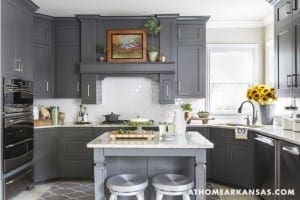 Gray kitchen with white subway tile, island, and sunflowers.