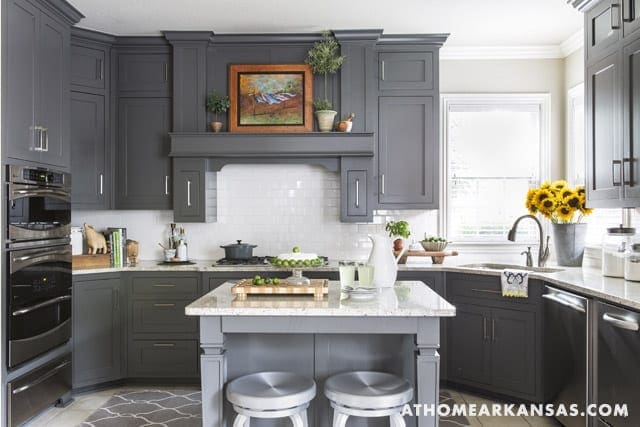 Gray kitchen with white subway tile, island, and sunflowers.