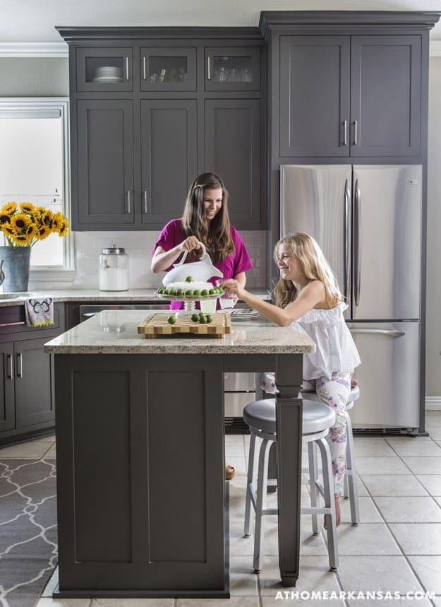 Gray kitchen cabinets with stainless steel refrigerator and island.
