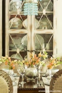 White cabinet with glass doors and turquoise accents, floral arrangement.