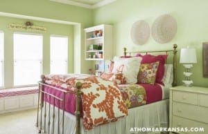Green bedroom with a brass bed frame and pink bedding.
