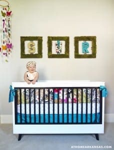 Crib with patterned bedding and moss-covered framed letters.