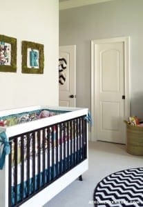 Dark wood crib with colorful patterned bedding and a woven basket.
