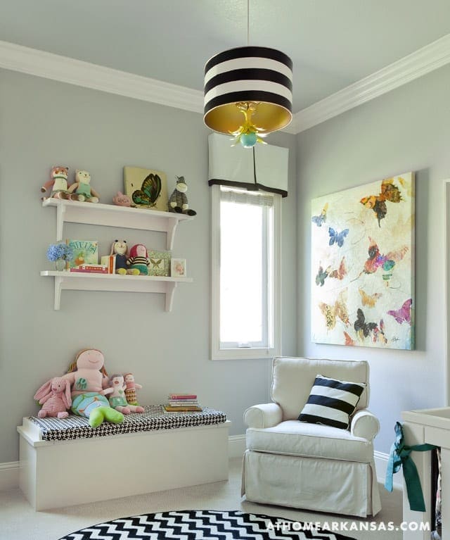 Gray bedroom with striped pendant light, shelf, and armchair.