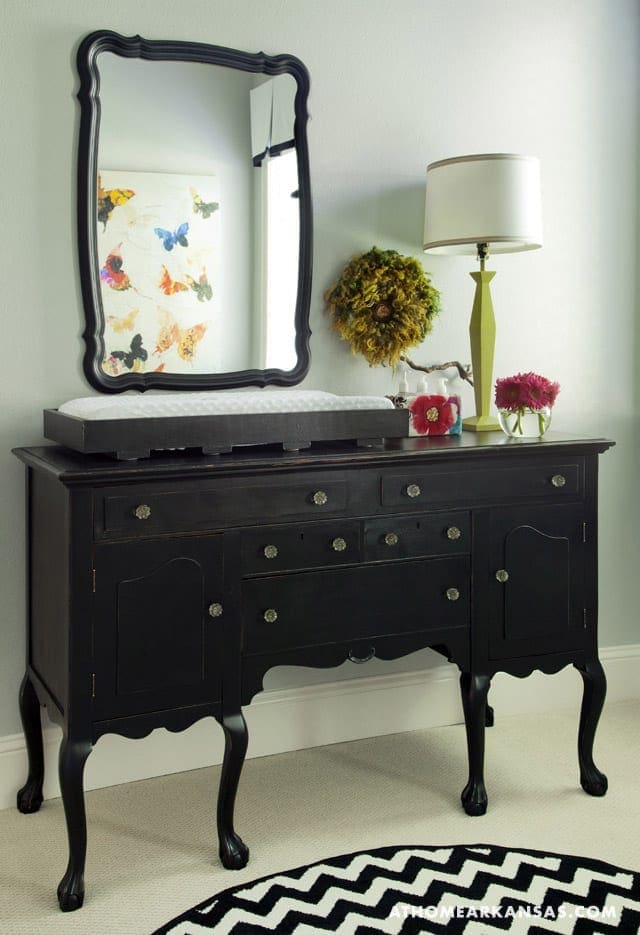 Black dresser with a mirror and floral lamp.