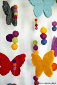 Colorful felt butterflies hanging from white strings.