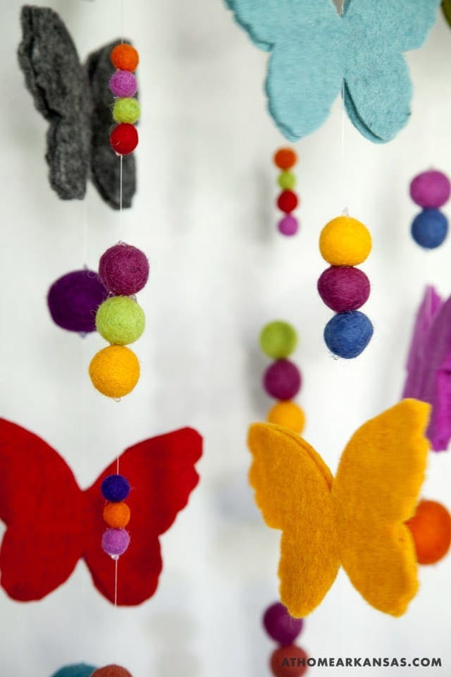 Colorful felt butterflies hanging from white strings.