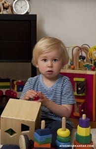 Toddler playing with wooden blocks and toy car.
