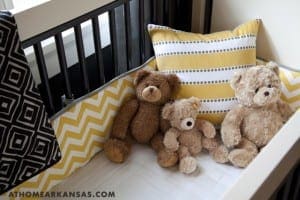 Black crib with yellow and gray striped bedding and teddy bears.