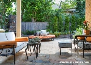 Outdoor patio with orange seating, patterned cushions, and a stone floor.