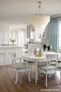 White kitchen with shell chandelier, dining table, and chairs.