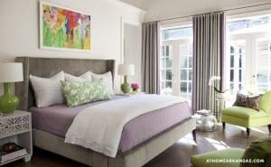 Gray upholstered bed in a light-filled bedroom with purple accents.