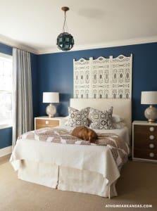 Blue wall bedroom with white headboard and patterned pillows.