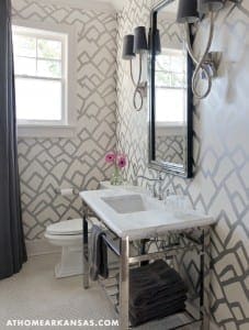 Gray and white geometric wallpapered powder room with marble sink.
