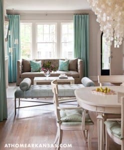 Light-filled living room with teal curtains, sofa, and dining table.