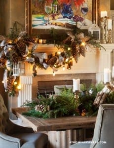 Mantel decorated with pinecones, greenery, and candles.