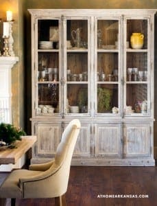 Large, distressed wooden cabinet displays china and glassware.