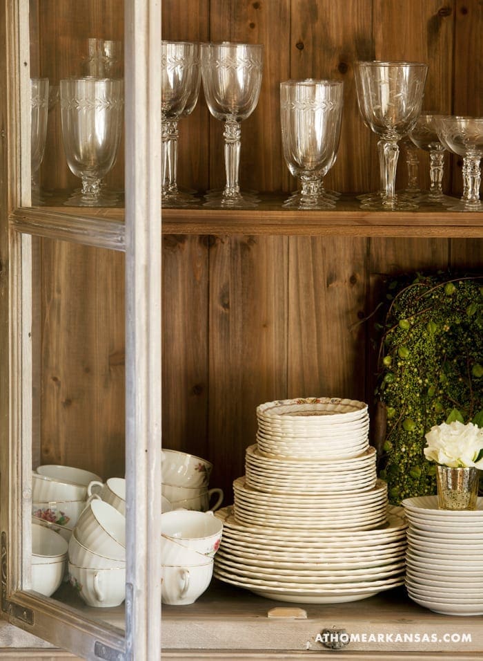 Wooden cabinet with glassware, plates, and china.