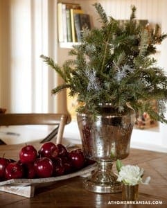 Silver urn with pine branches, apples, and white flowers.