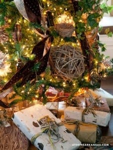Wrapped gifts and a bird's nest with lights under a tree.