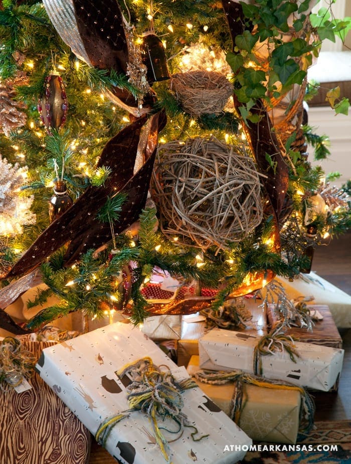Wrapped gifts and a bird's nest with lights under a tree.