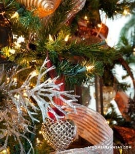 Silver and red Christmas ornament on decorated tree branch.