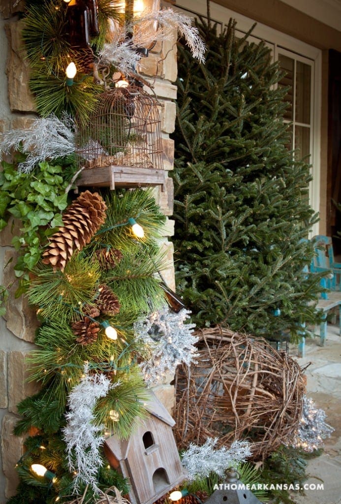 Stone pillar decorated with greenery, pine tree, and lights.