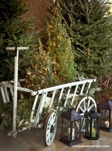 Outdoor Christmas scene with trees, wagon, and lanterns.