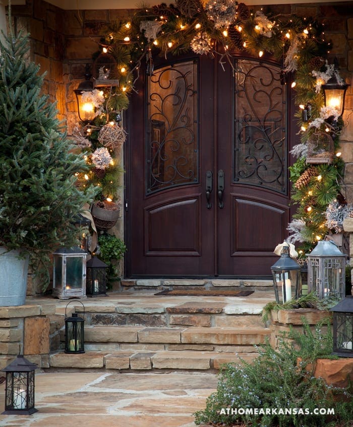 Stone entryway with arched doors, string lights, and lanterns.