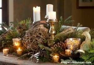 Gold candlestick holder with candles, greenery, and decorative objects.